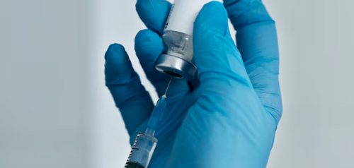 Gloved hand preparing a syringe for vaccination